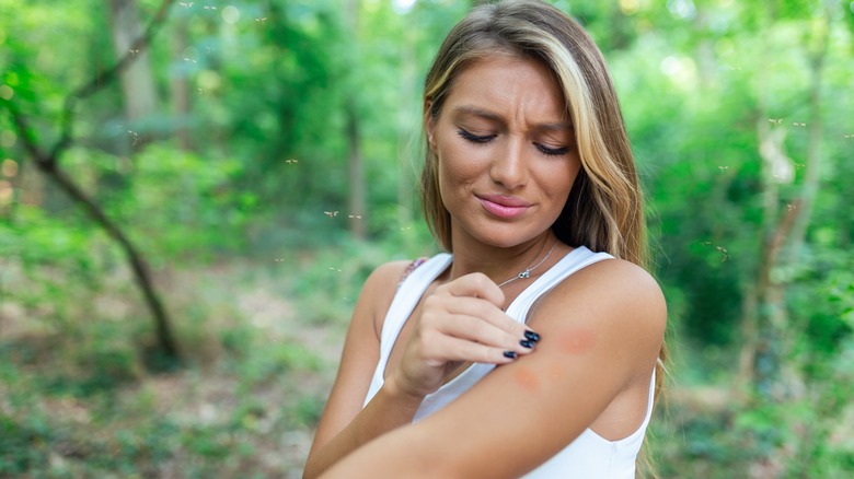woman looking at mosquito bite on arm