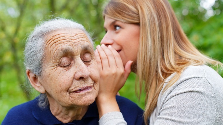 a woman whispering to an old lady