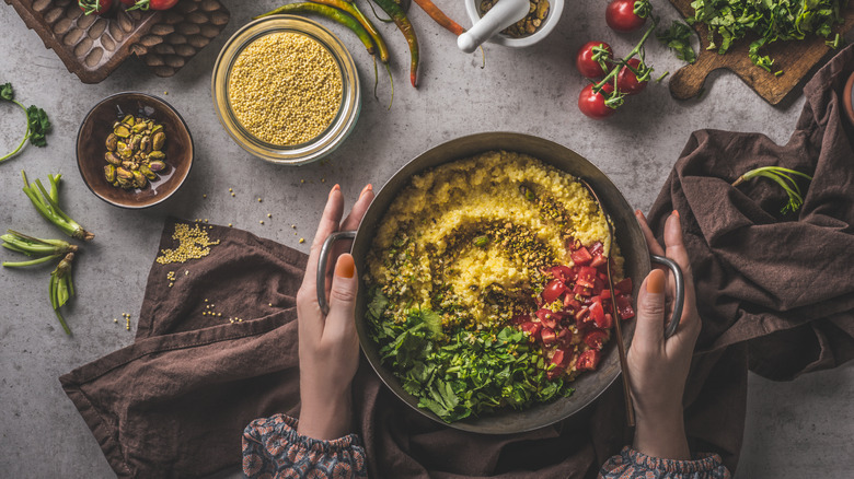 bowl of cooked millet with tomatoes and herbs