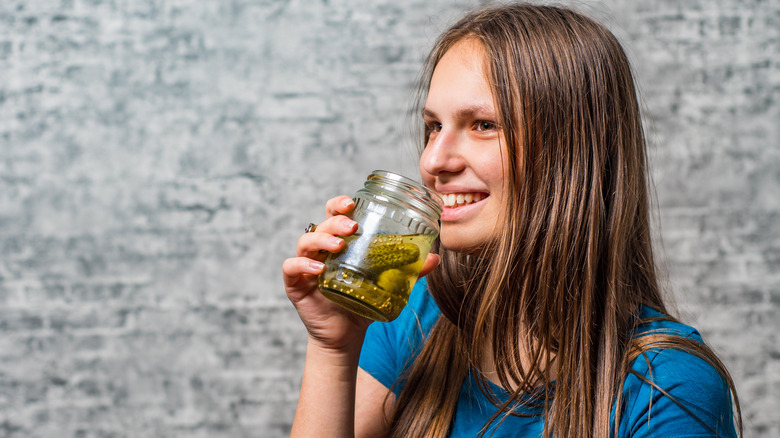 young girl drinking pickle brine from a jar