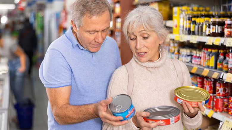 Older couple looking at the labels of canned goods