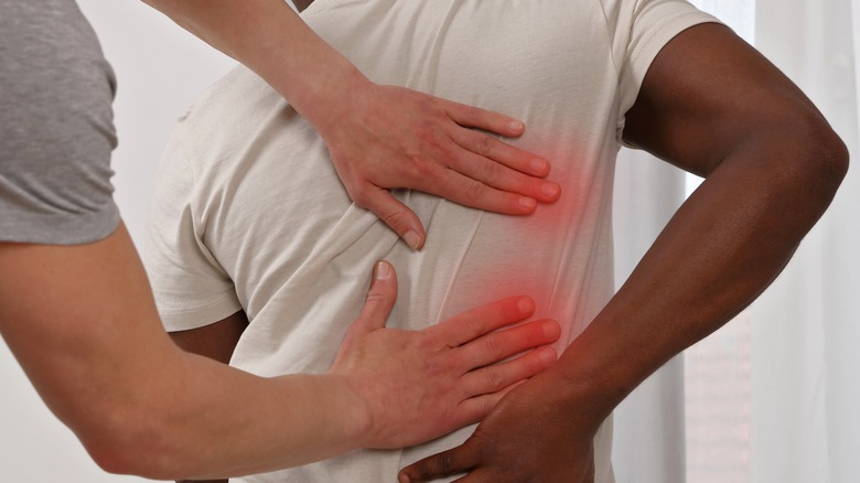 Physical therapist pushing on patient's back