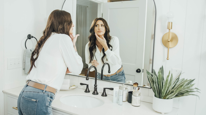 Woman looking at skin in mirror