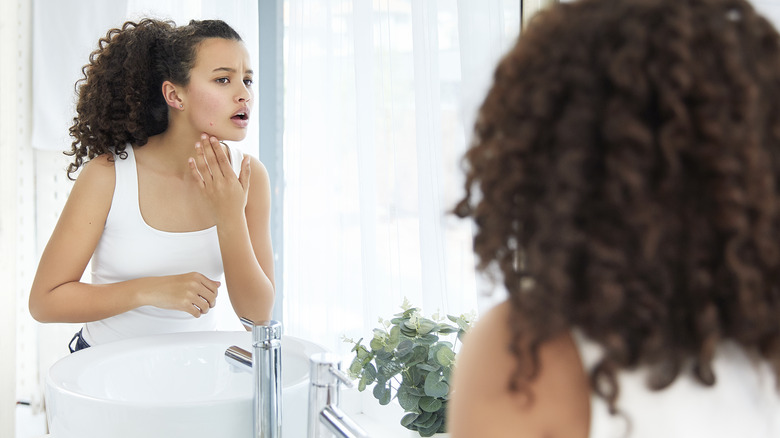 Woman looking at irritated skin in mirror