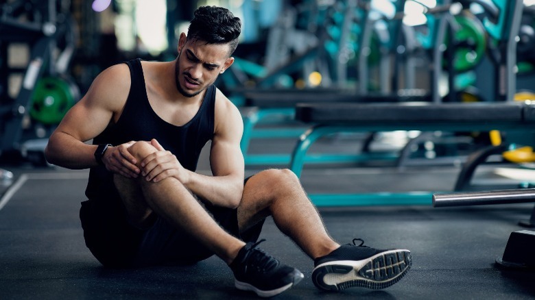 man holding knee in gym