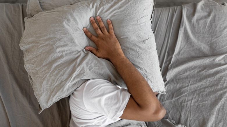 Person covers head with pillow
