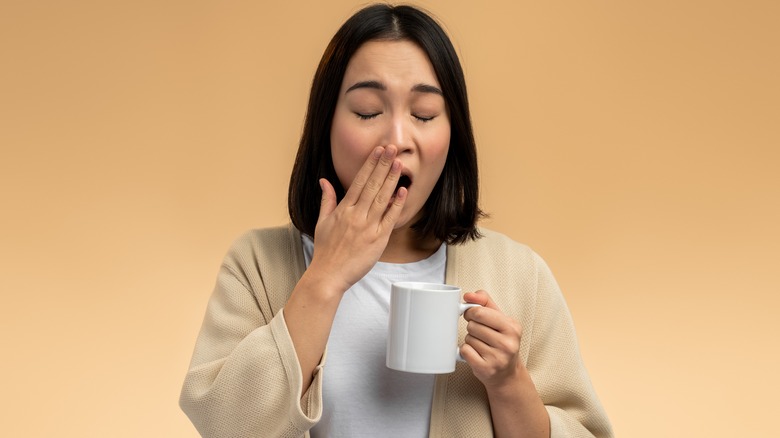 woman holding a mug and yawning