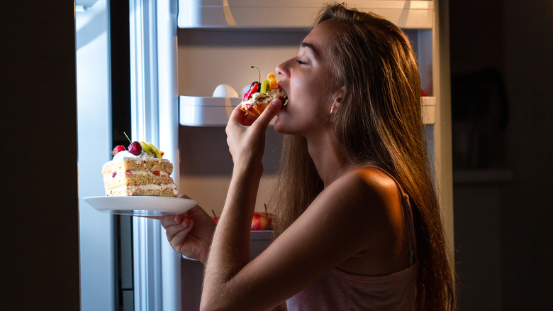 woman eating cake straight from the fridge