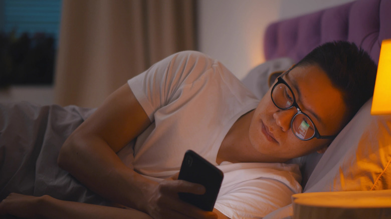 man looking at his phone while in bed