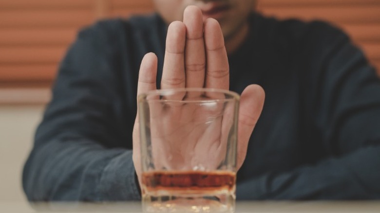 Man holding up hand to alcohol