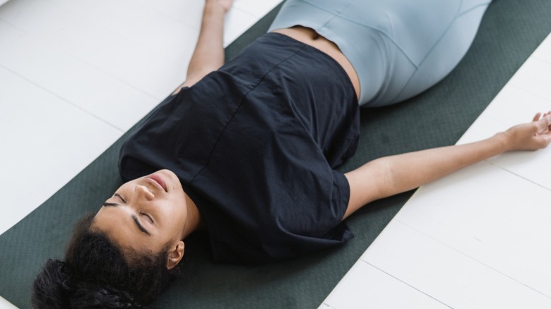 Young woman lying on yoga mat