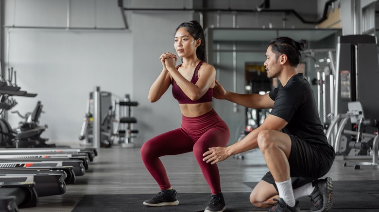 trainer helping woman with form