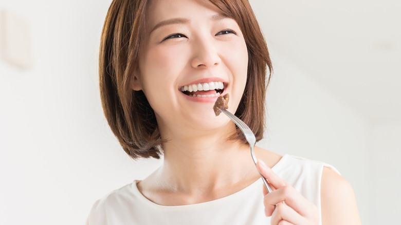 Asian woman eating and smiling
