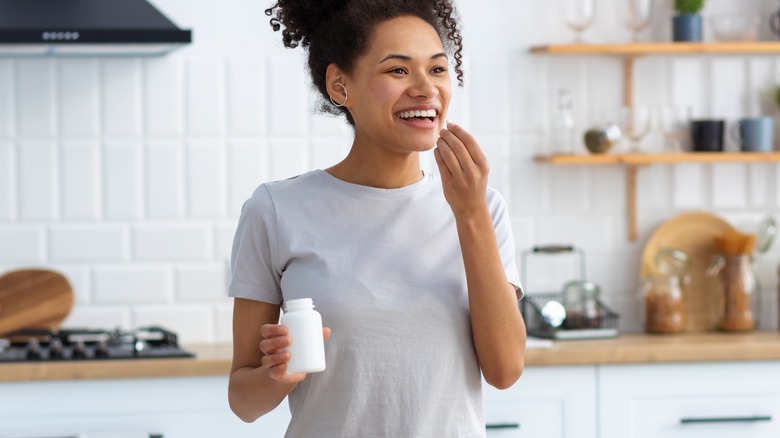 woman in kitchen taking supplements