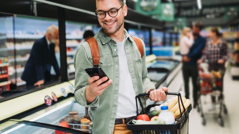 man buying groceries and using phone