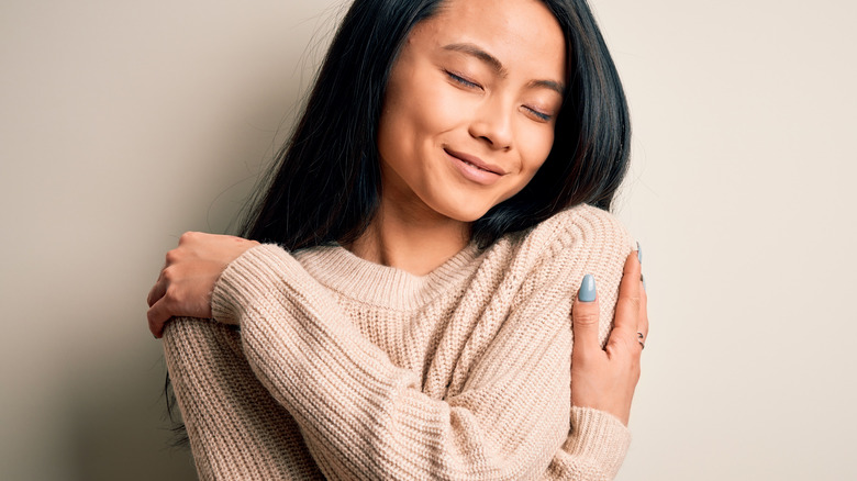 happy woman hugging self