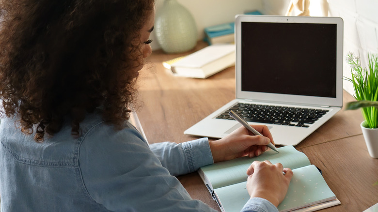 woman writing goals in notebook