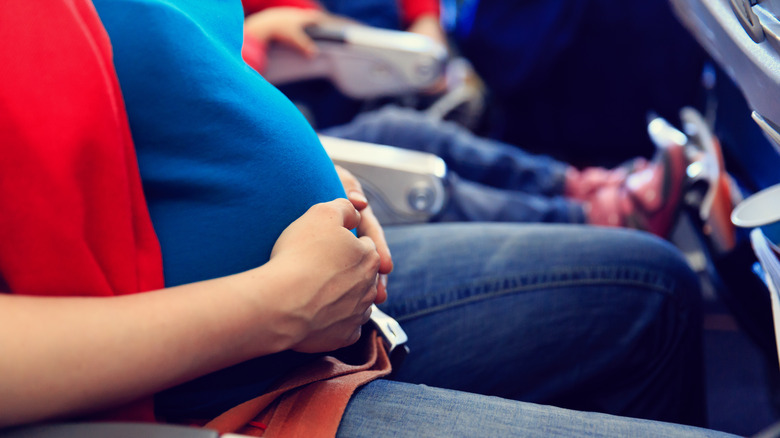 Pregnant person wearing seatbelt on plane