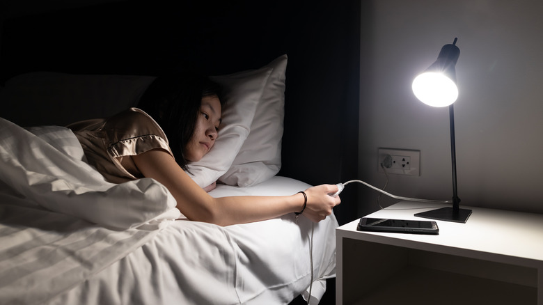 woman in bed switching off tablelamp