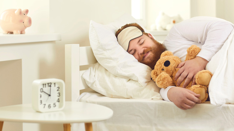 man sleeping in bed with a teddy bear