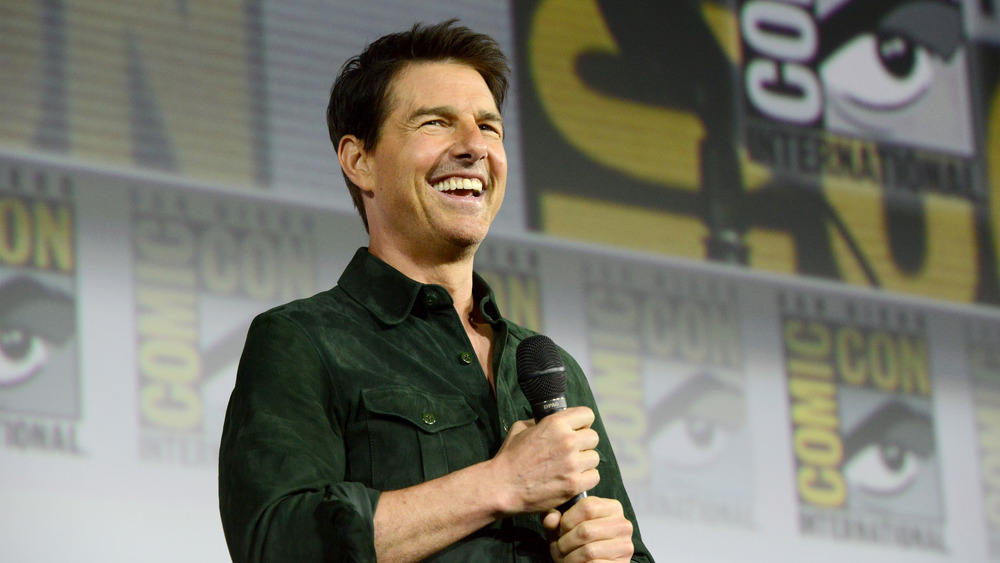 Actor Tom Cruise smiling while holding a microphone 