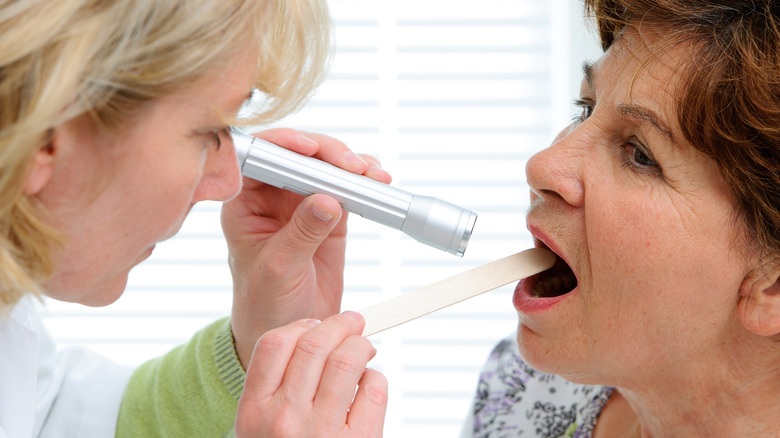 doctor examining older female patient's throat 