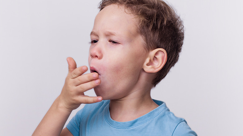 young boy coughing with white background