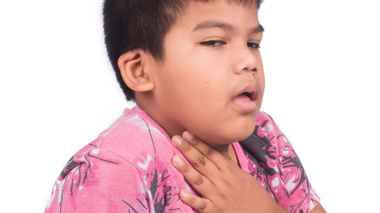 asian boy holding sore throat