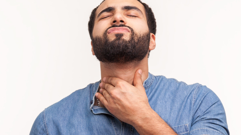 man with beard touching his throat
