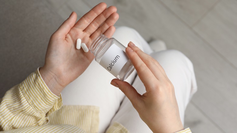 Person holding supplements from "calcium" bottle