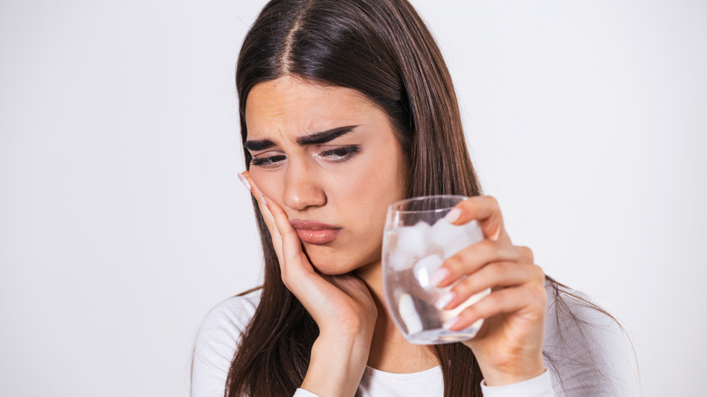 Young woman holding sensitive mouth from cold drink