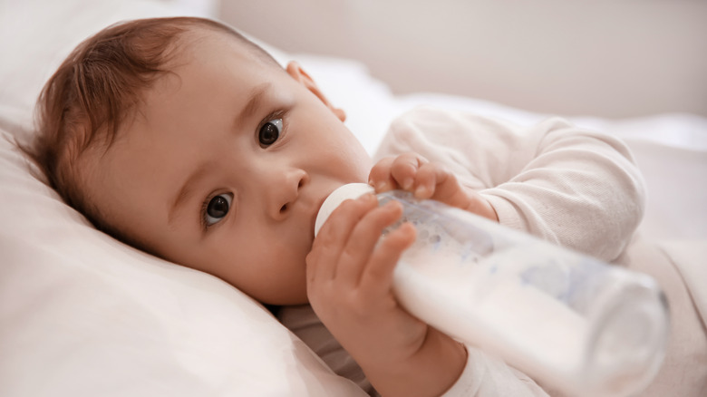 Infant in crib sucking bottle of milk