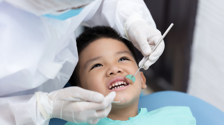 Asain boy in dental chair with dental professional looking into his mouth