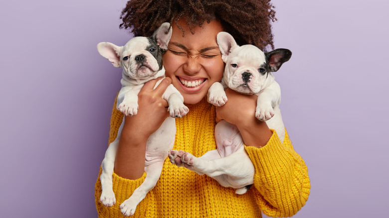 Black woman cuddling two puppies