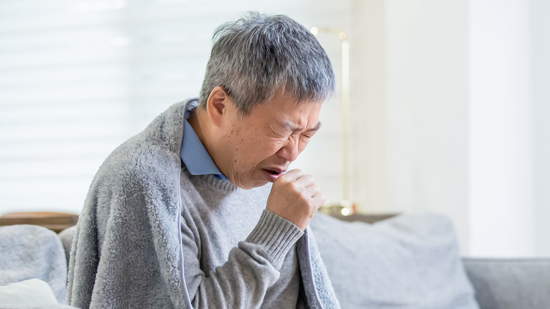 Old Asian man coughing from cold 