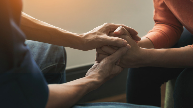 Woman comforting woman with hands on back