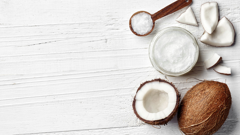 a jar of coconut oil, a spoon, and a coconut