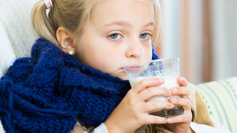 a little girl with a sore throat and a blue scarf