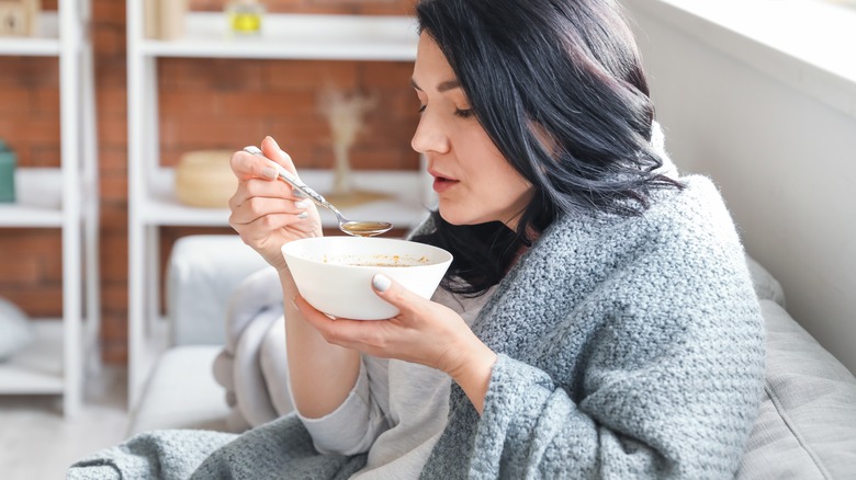  woman who is sick, drinking soup