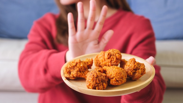 Woman rejecting a plate of fried chicken