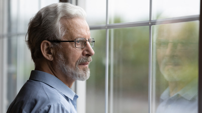 Elderly man gazing out window