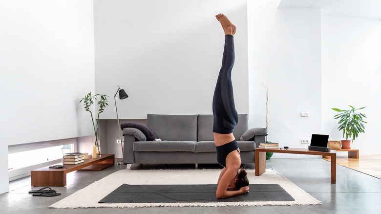 woman practicing a headstand in her living room