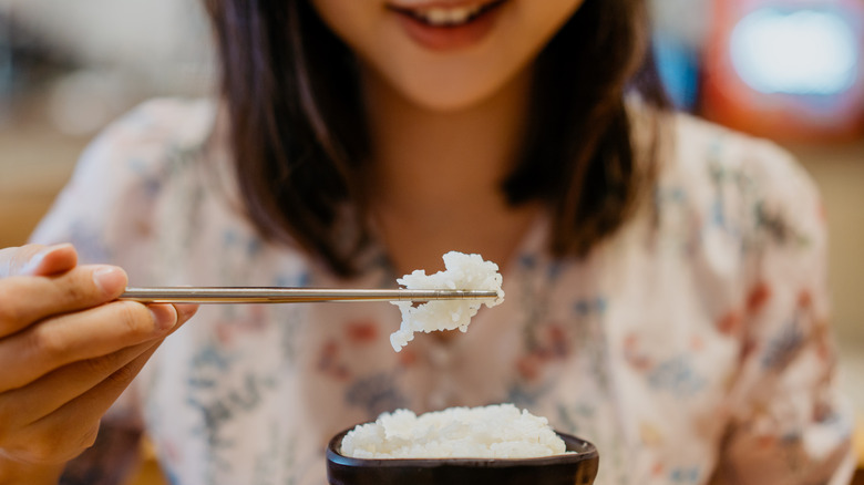 Woman eating white rice with chopsticks