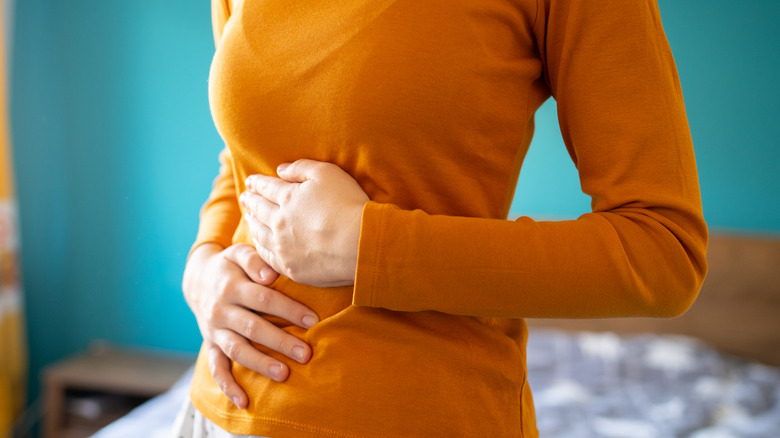 A woman's two hands holding her abdomen