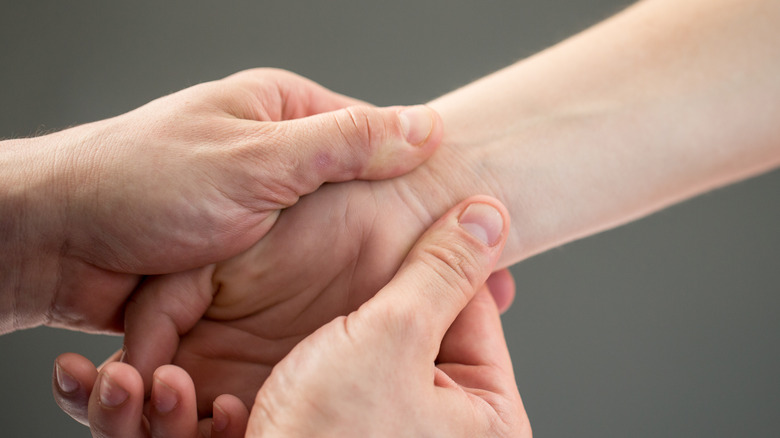 therapist's two hands pressing into the inner wrist of a patient's inner wrist