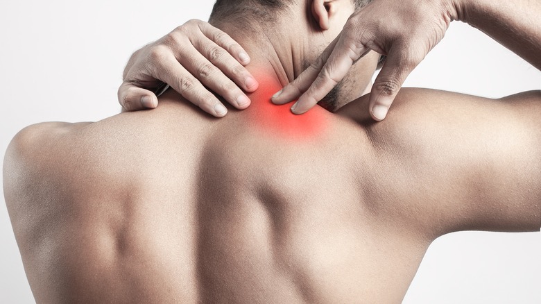 man pressing into his trapezius muscle