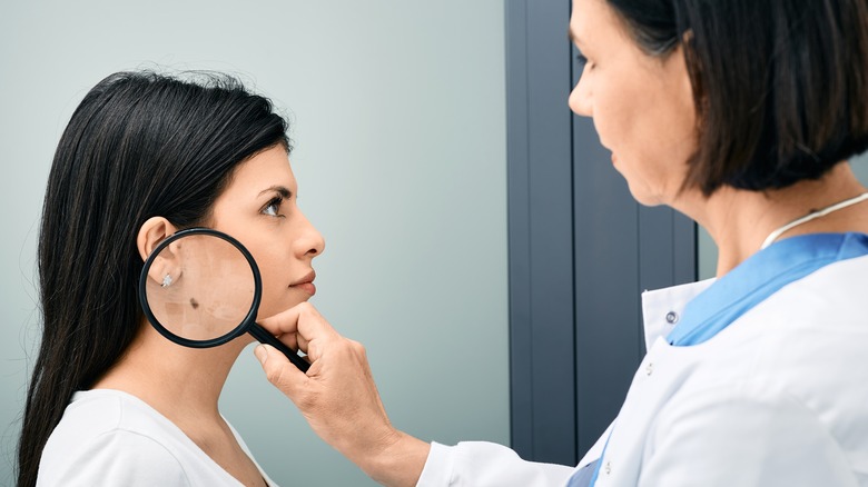 Dermatologist examining mole on patient