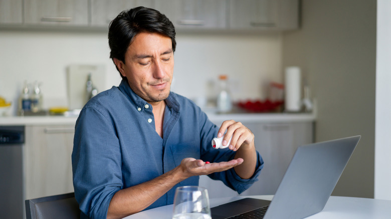 A man pouring out some supplement tablets from a bottle