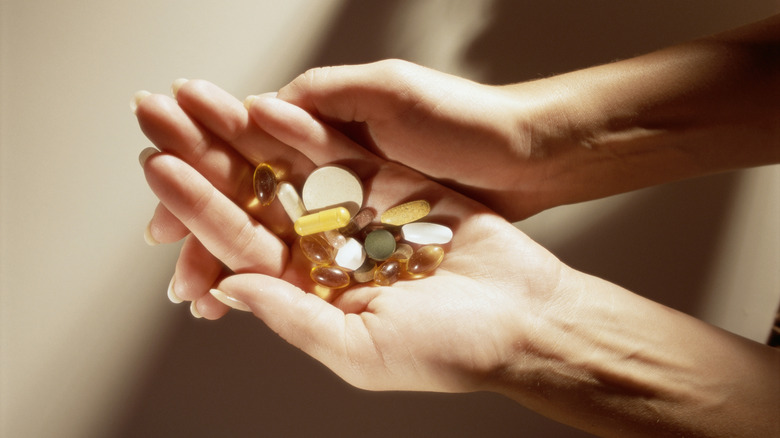 A woman's hands holding a variety of supplements