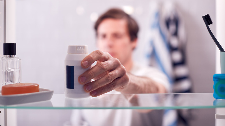 man reaching inside medicine cabinet